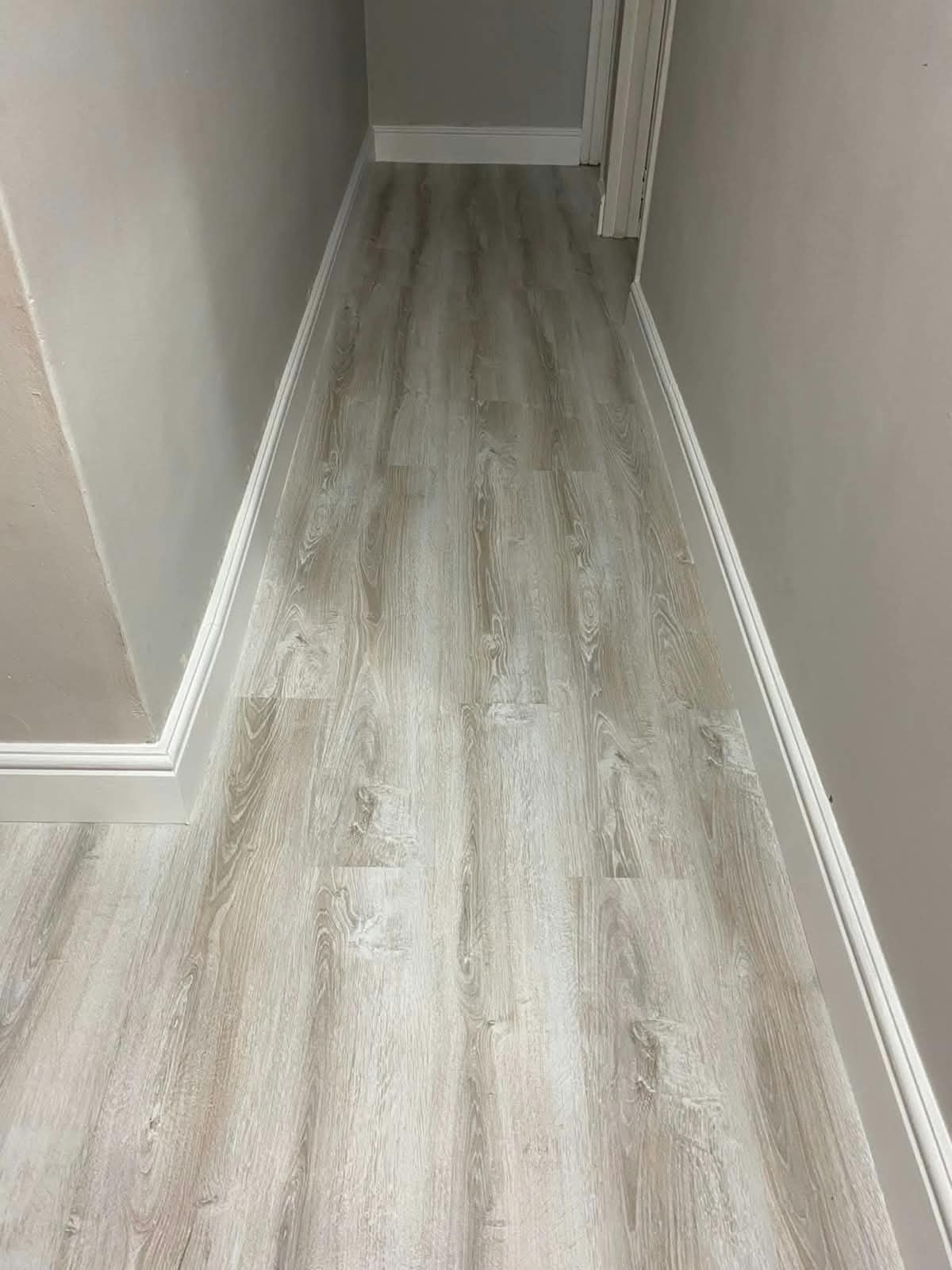Grey wood-look vinyl or laminate flooring in a hallway