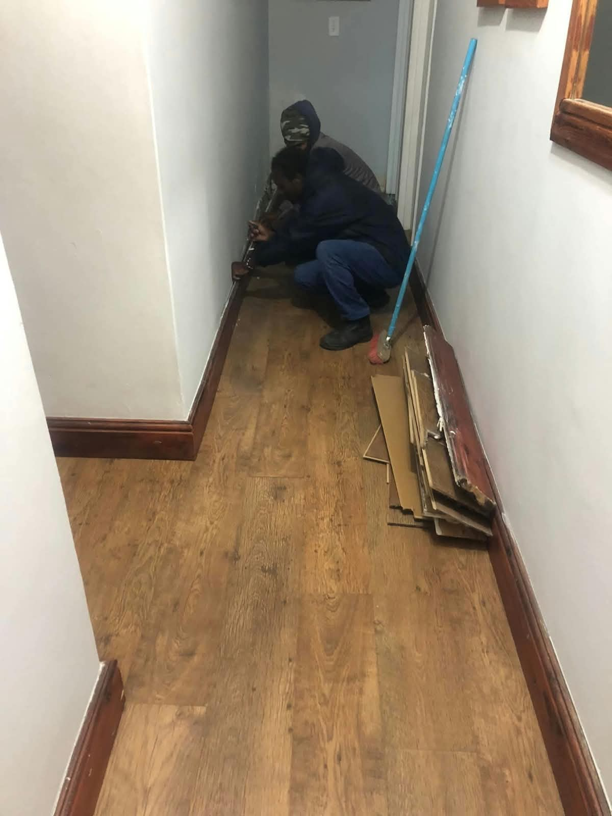 WBS RenCon installer fitting laminate flooring in a narrow hallway