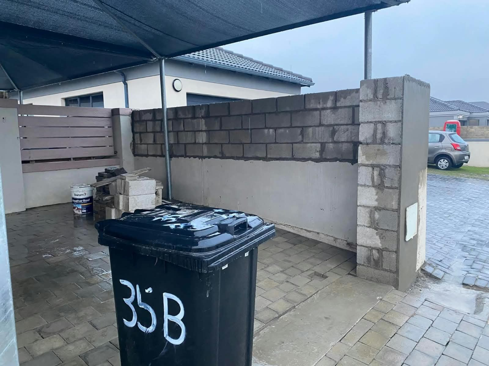 Boundary wall with plastered and block sections under a carport