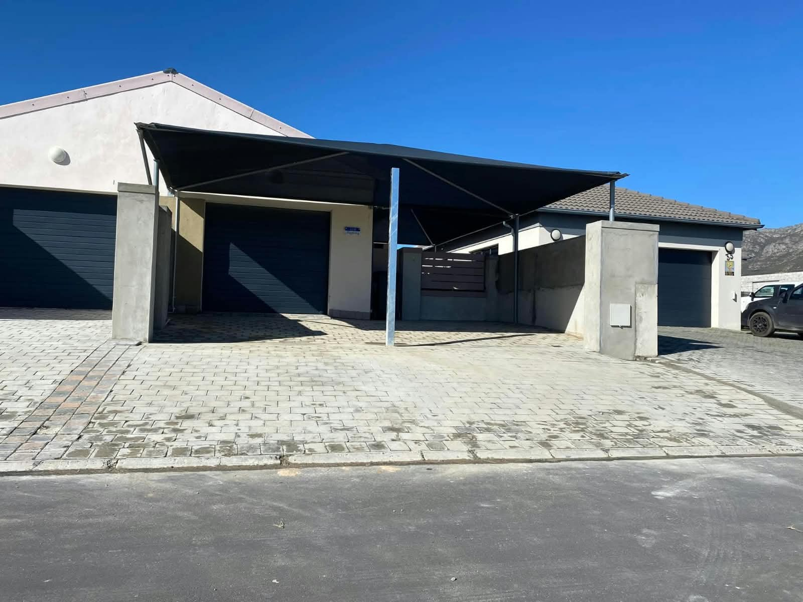 Completed carport with paved driveway and plastered pillars