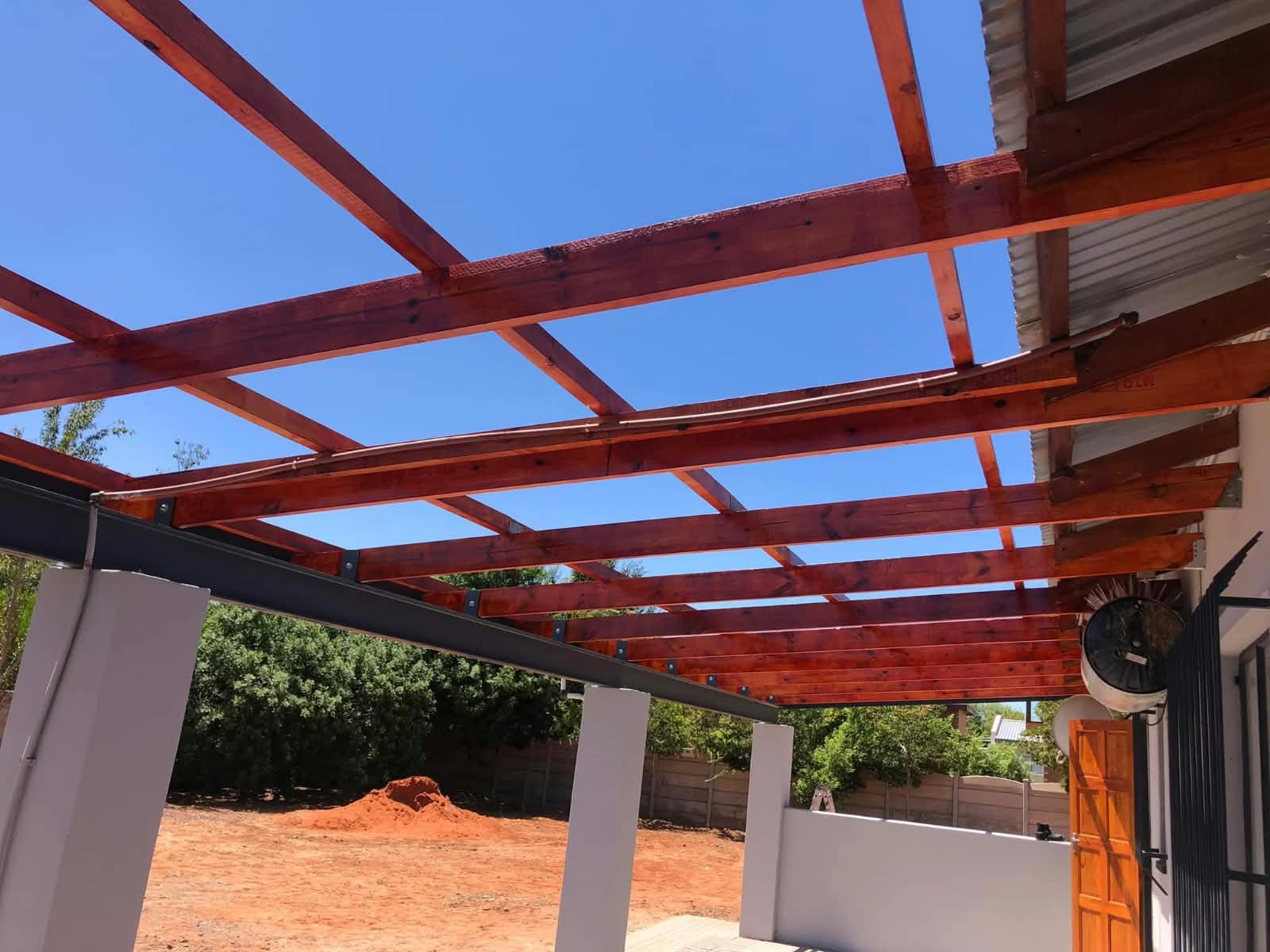 Timber pergola beams against a clear sky